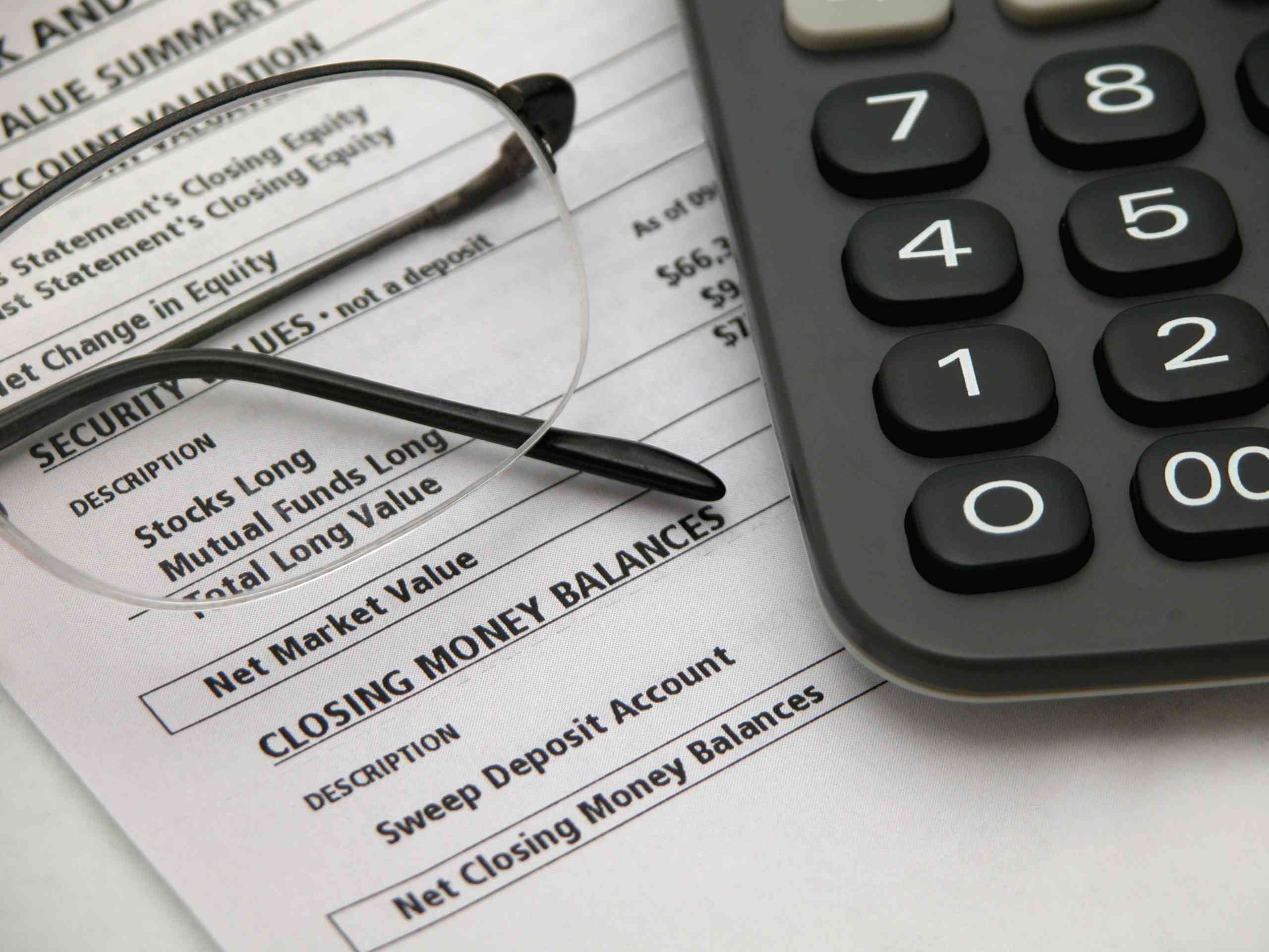 A financial statement with glasses and calculator on the desk.