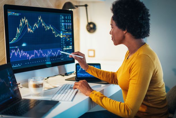 Woman checking stock market charts on a computer monitor