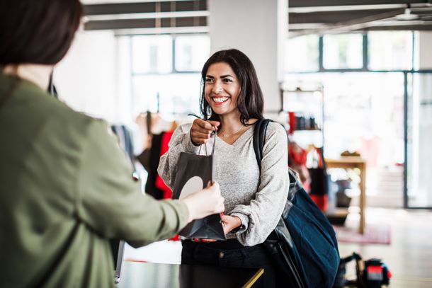 Shopper in a clothing store handing a bag to a sales clerk