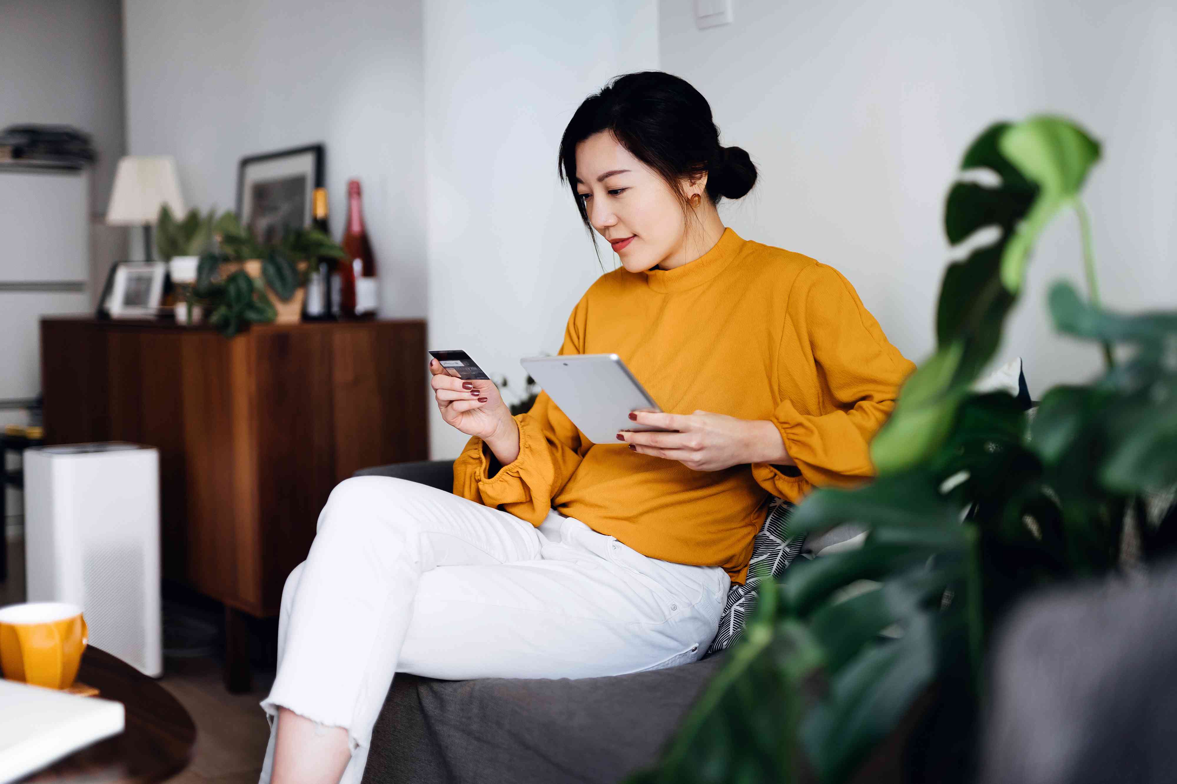 Woman handling bank account and financial bills with digital tablet and credit card at home